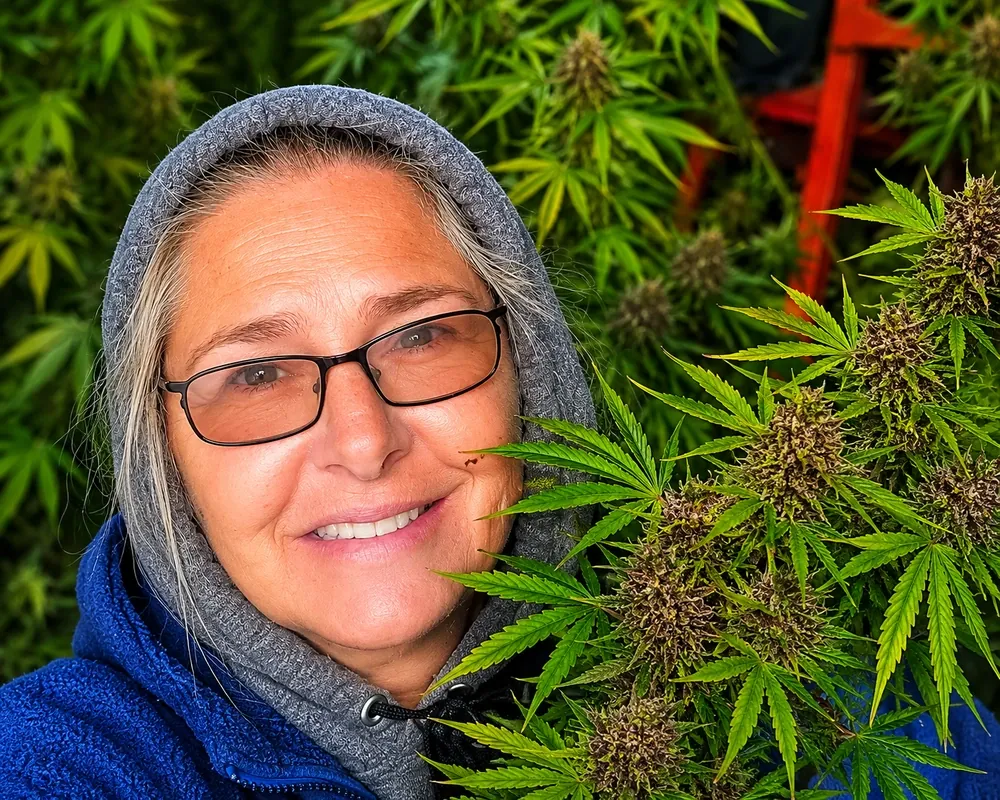 Yolanda smiling beside hemp plants